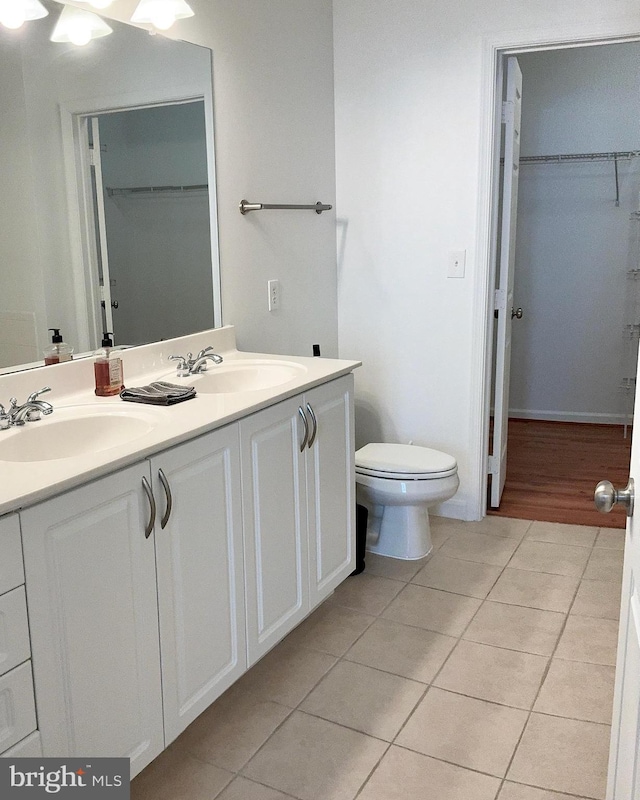 full bath featuring double vanity, tile patterned flooring, toilet, and a sink