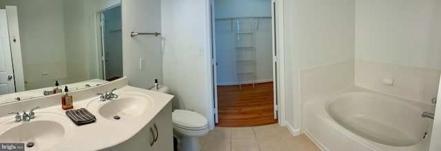 full bathroom featuring a garden tub, tile patterned flooring, a sink, and toilet