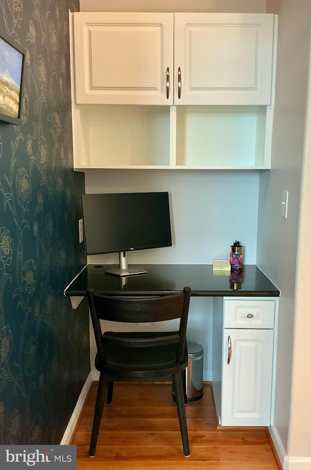 office area featuring baseboards, built in desk, wood finished floors, and wallpapered walls