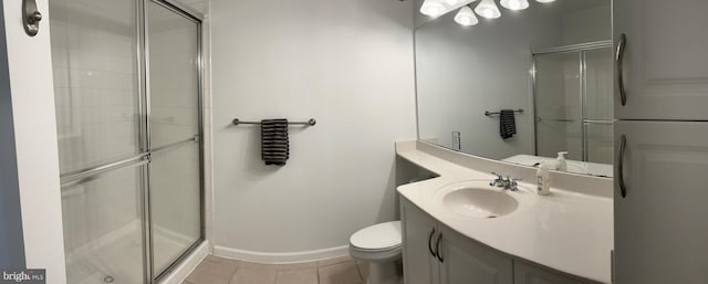 bathroom with toilet, vanity, baseboards, a shower stall, and tile patterned floors