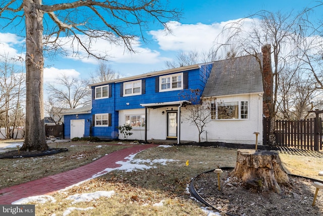 view of front of house featuring brick siding, a chimney, and fence