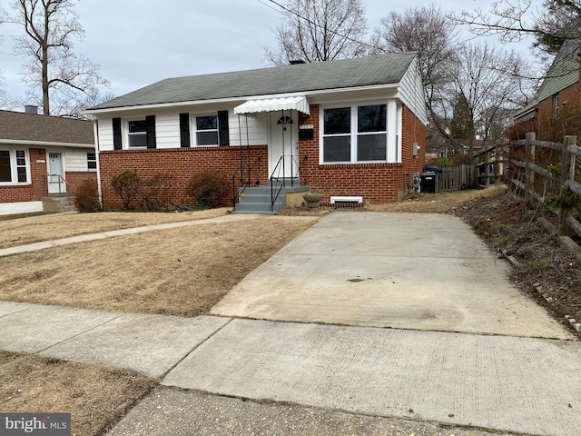 bungalow featuring roof with shingles, fence, and brick siding