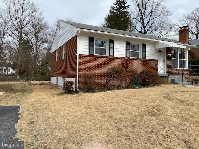 view of front facade with driveway, a chimney, a front lawn, and brick siding