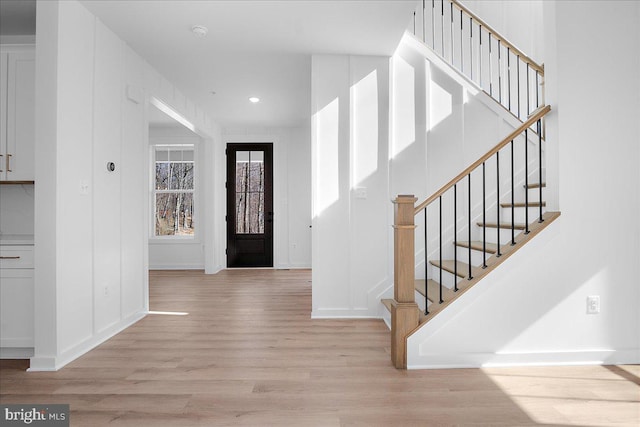 foyer entrance featuring light wood finished floors, baseboards, stairway, and recessed lighting