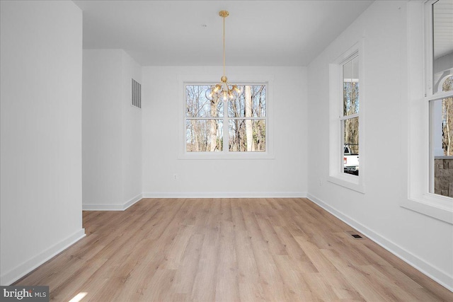 unfurnished dining area with a chandelier, visible vents, baseboards, and wood finished floors