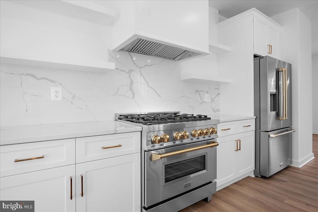 kitchen with light stone counters, open shelves, stainless steel appliances, custom range hood, and white cabinets