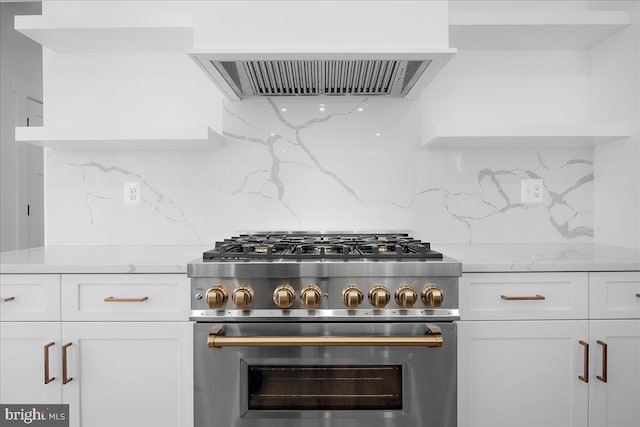 kitchen featuring light stone counters, decorative backsplash, white cabinetry, high end range, and extractor fan