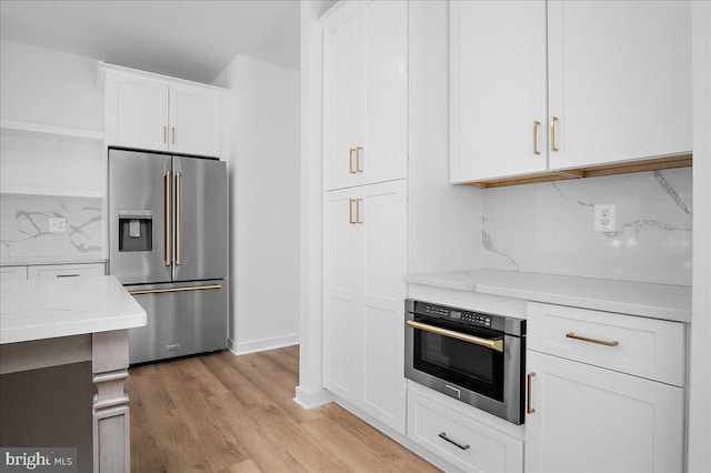 kitchen with light wood-style flooring, white cabinetry, appliances with stainless steel finishes, open shelves, and tasteful backsplash