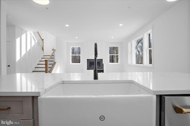 interior details featuring light stone counters, a sink, and recessed lighting