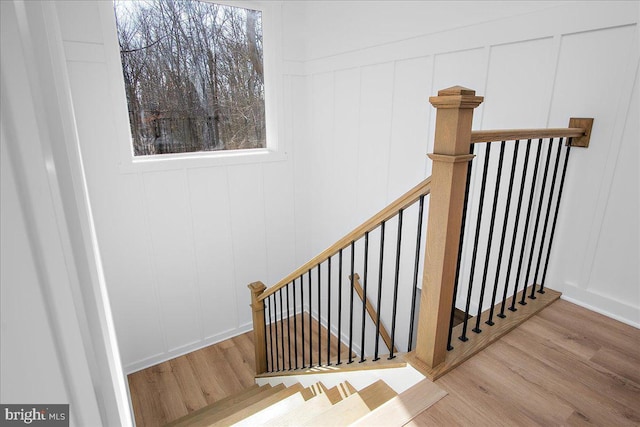 staircase featuring wood finished floors and a decorative wall