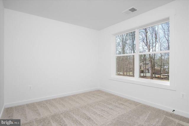 spare room featuring carpet flooring, visible vents, and baseboards