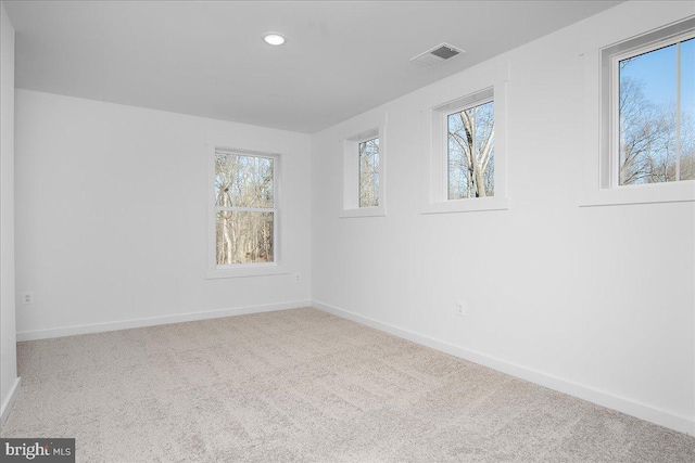 unfurnished room featuring carpet, visible vents, plenty of natural light, and baseboards