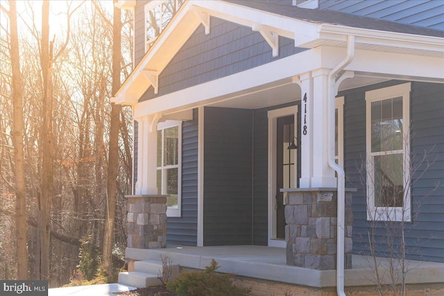 property entrance with stone siding and a porch