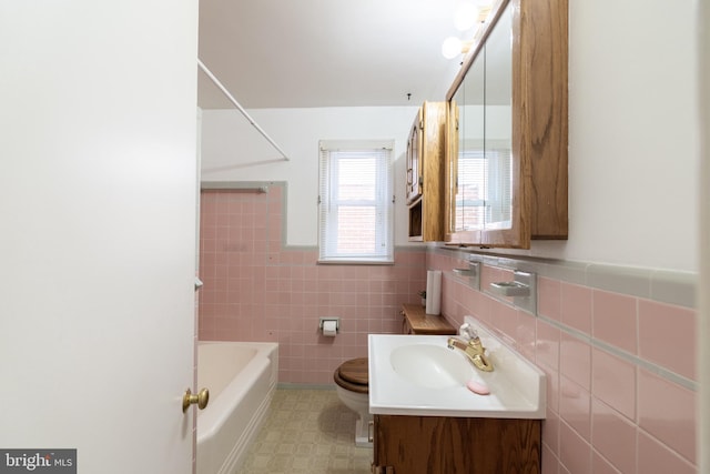 bathroom featuring toilet, a wainscoted wall, vanity, and tile walls