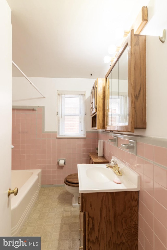 full bath featuring toilet, a wainscoted wall, vanity, tile walls, and shower / bathing tub combination