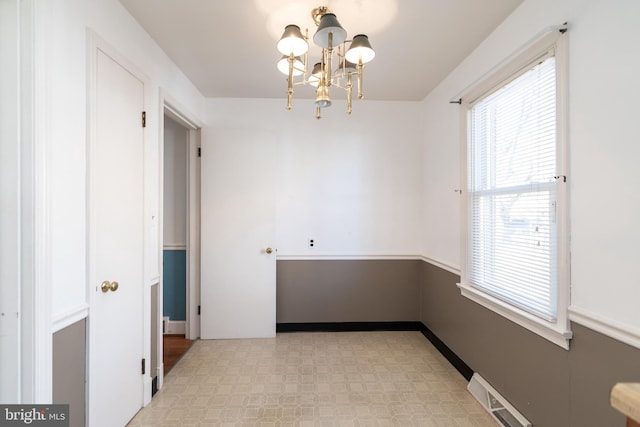 empty room featuring an inviting chandelier, baseboards, visible vents, and light floors