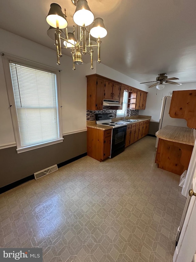 kitchen with light floors, visible vents, brown cabinets, and range with electric stovetop