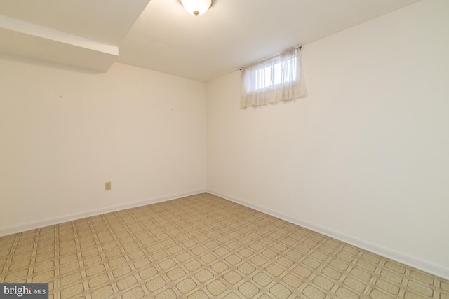 spare room featuring light floors and baseboards