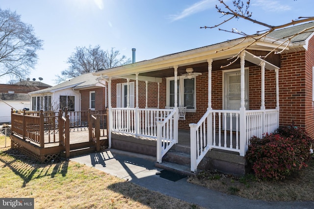 view of front of house with ceiling fan, brick siding, and a porch