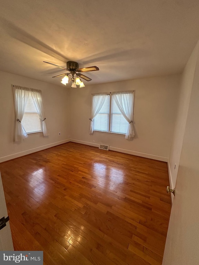 unfurnished room featuring plenty of natural light, baseboards, and wood finished floors