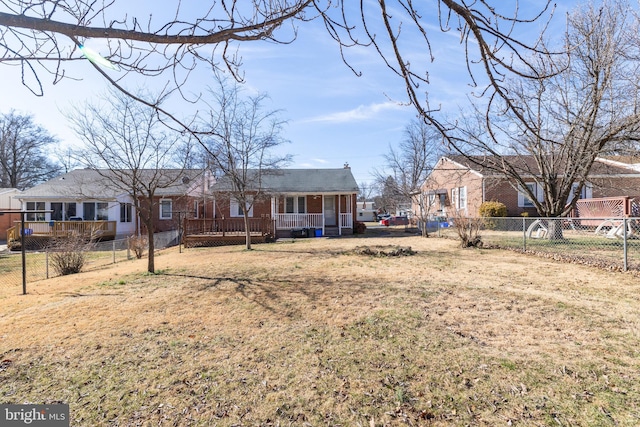 view of front of home with a wooden deck, a fenced backyard, a front lawn, and brick siding