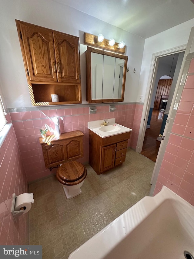 bathroom featuring tile walls, toilet, wainscoting, vanity, and tile patterned floors