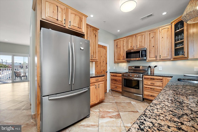 kitchen featuring recessed lighting, visible vents, appliances with stainless steel finishes, glass insert cabinets, and dark stone counters