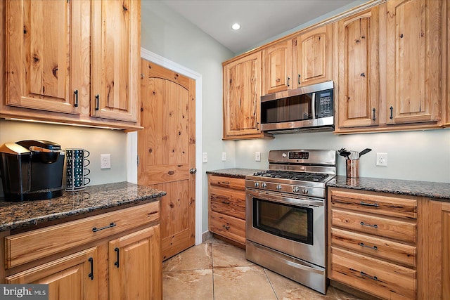 kitchen with appliances with stainless steel finishes, dark stone counters, and recessed lighting