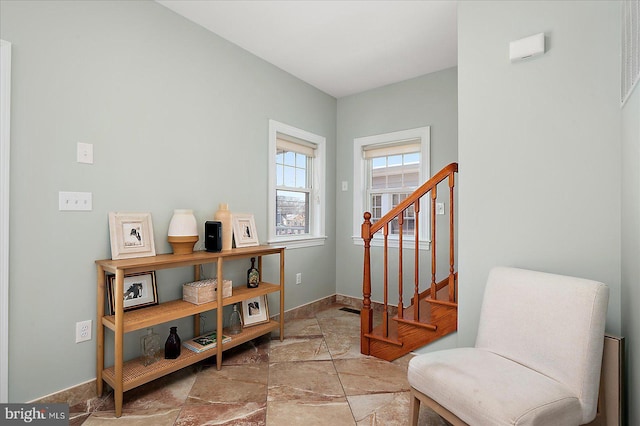 sitting room featuring stone tile flooring, stairway, and baseboards