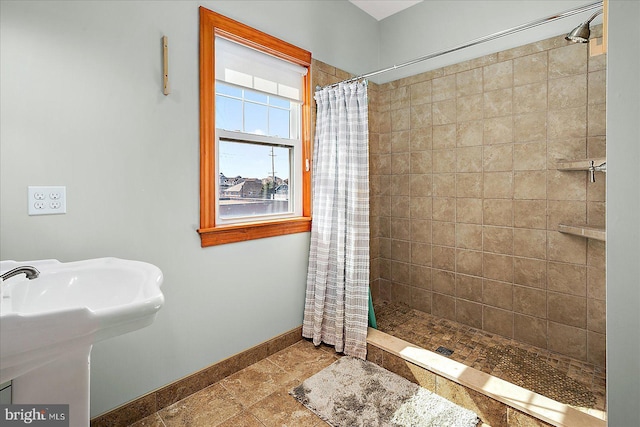 full bath featuring tiled shower and baseboards