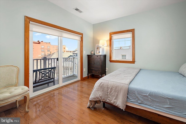 bedroom featuring access to outside, wood finished floors, visible vents, and baseboards