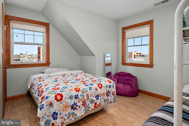 bedroom featuring lofted ceiling, wood finished floors, visible vents, and baseboards