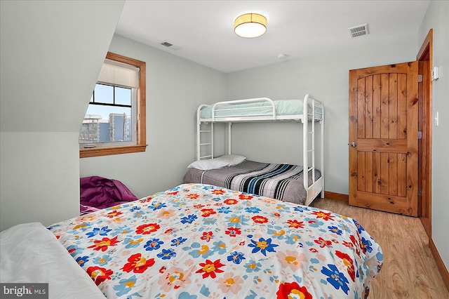 bedroom featuring baseboards, visible vents, and wood finished floors