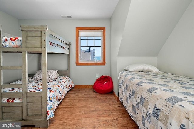 bedroom with visible vents, baseboards, and wood finished floors