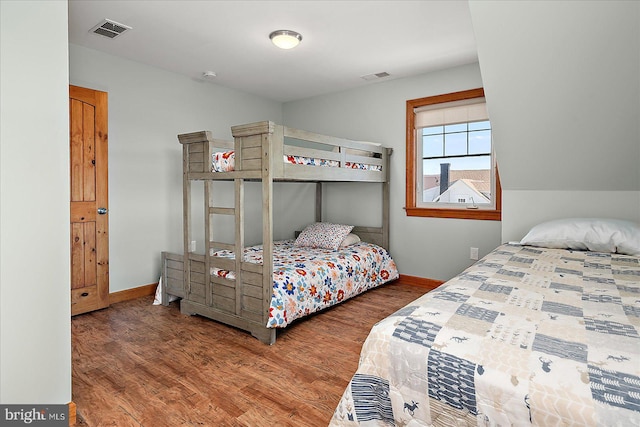 bedroom featuring visible vents, baseboards, and wood finished floors