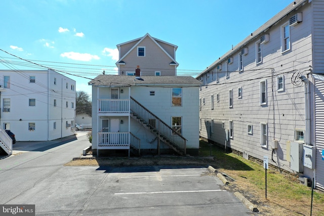 back of property with an AC wall unit and stairway