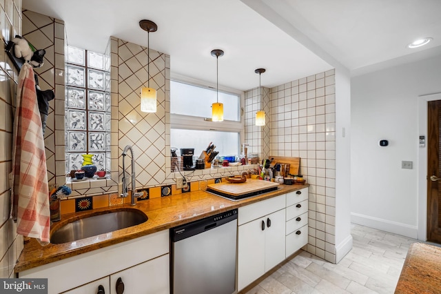 kitchen featuring a sink, tile walls, white cabinets, hanging light fixtures, and stainless steel dishwasher