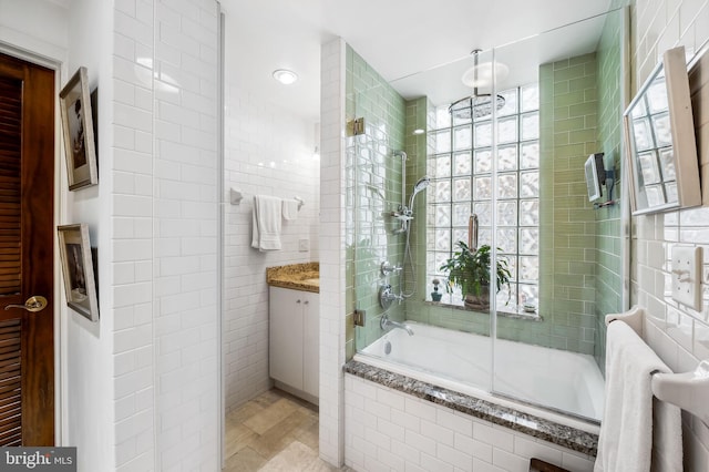 full bathroom featuring tiled shower / bath, vanity, and tile walls