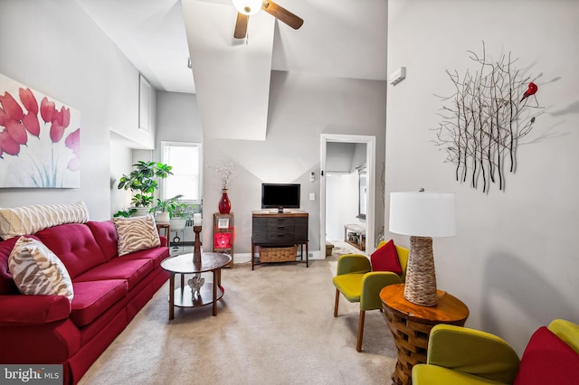 carpeted living area with a towering ceiling and ceiling fan