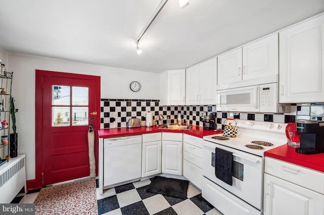 kitchen featuring dark floors, white appliances, white cabinetry, and radiator