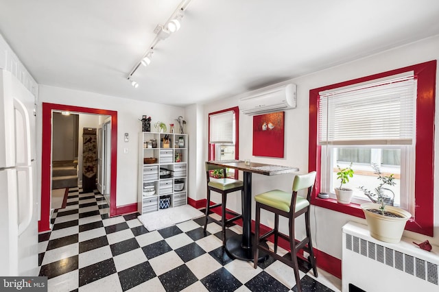 dining space featuring baseboards, radiator heating unit, tile patterned floors, track lighting, and a wall mounted AC