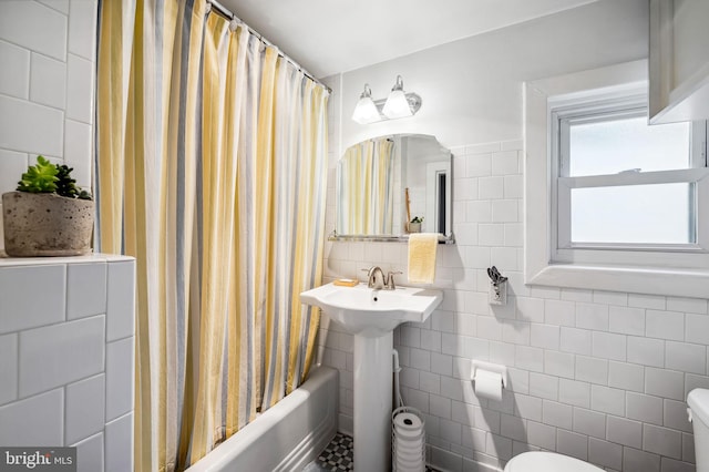 bathroom with toilet, shower / tub combo, and tile walls