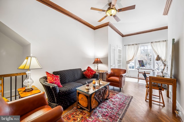 living area with baseboards, wood finished floors, a ceiling fan, and crown molding