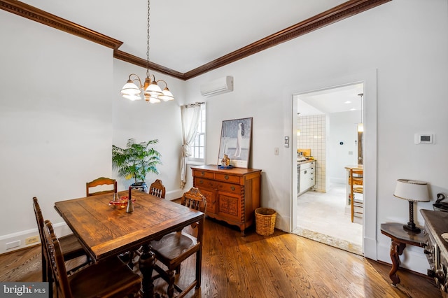 dining room featuring baseboards, a wall unit AC, wood finished floors, crown molding, and a chandelier