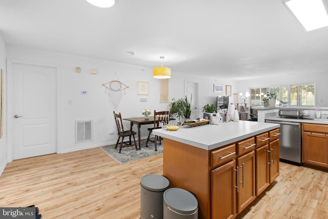 kitchen with visible vents, a center island, light countertops, light wood-type flooring, and stainless steel dishwasher