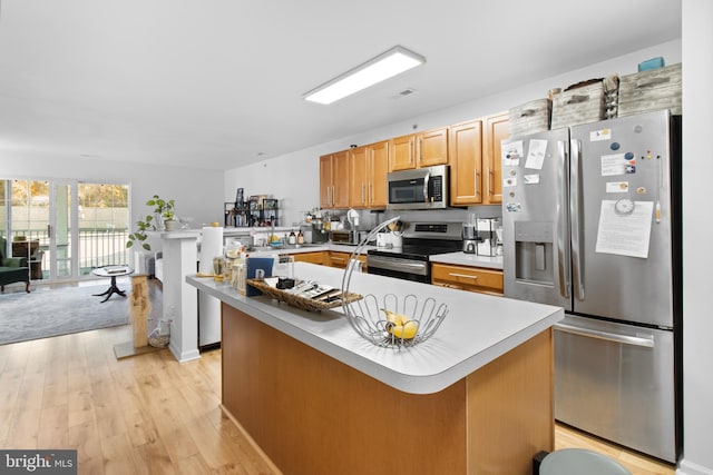 kitchen featuring a peninsula, visible vents, light countertops, appliances with stainless steel finishes, and light wood finished floors