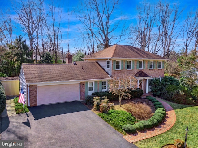 view of front of house with an attached garage, brick siding, driveway, roof with shingles, and a chimney