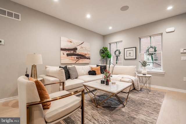 living room featuring light wood finished floors, baseboards, visible vents, and recessed lighting