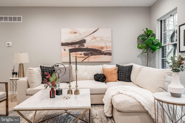 living room with baseboards, visible vents, and wood finished floors