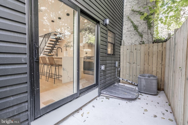 entrance to property featuring fence and central air condition unit